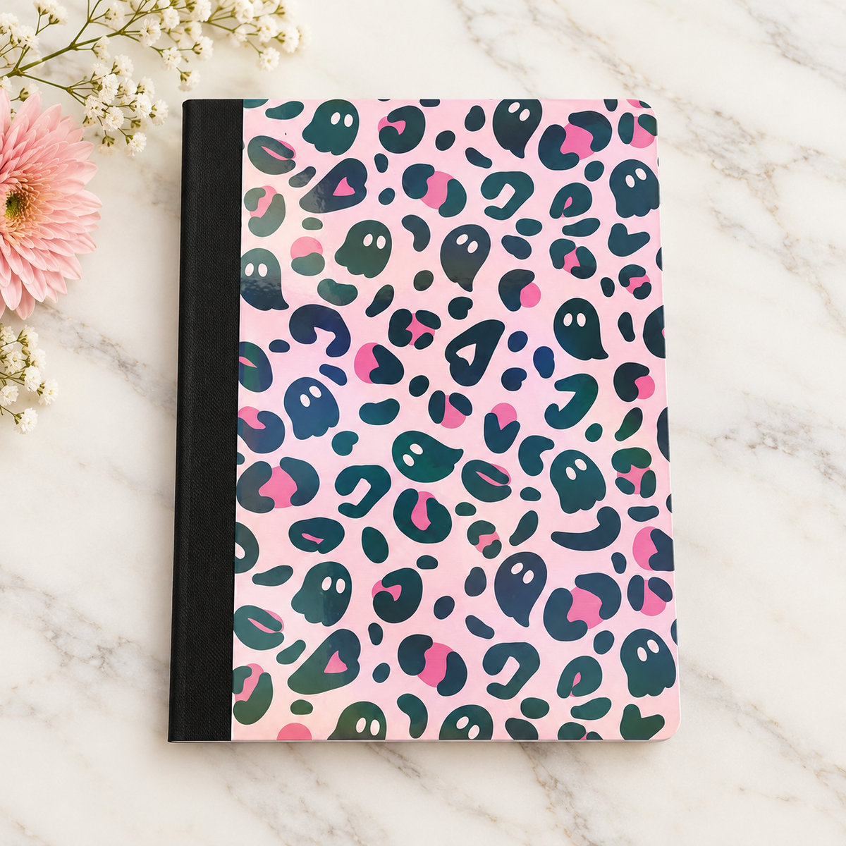 Pink composition book with dark teal ghost and leopard-inspired shapes and a black spine
